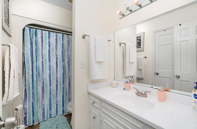 bathroom with curtained shower, vanity, and toilet