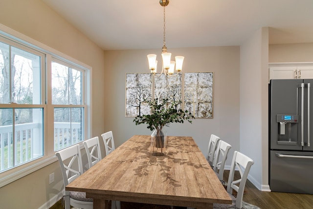 dining area with plenty of natural light, dark hardwood / wood-style floors, and an inviting chandelier