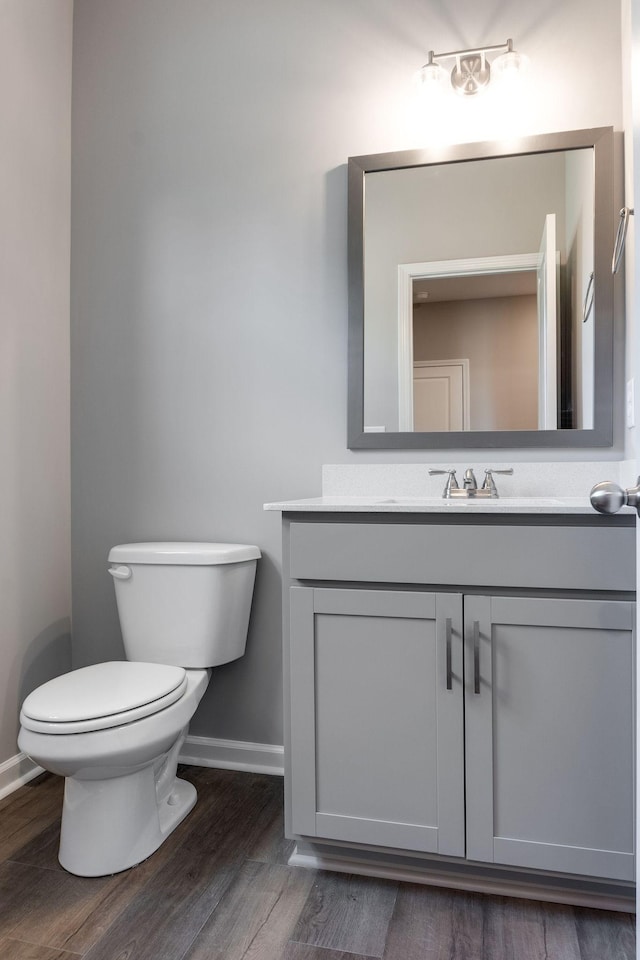 bathroom with toilet, vanity, and hardwood / wood-style floors