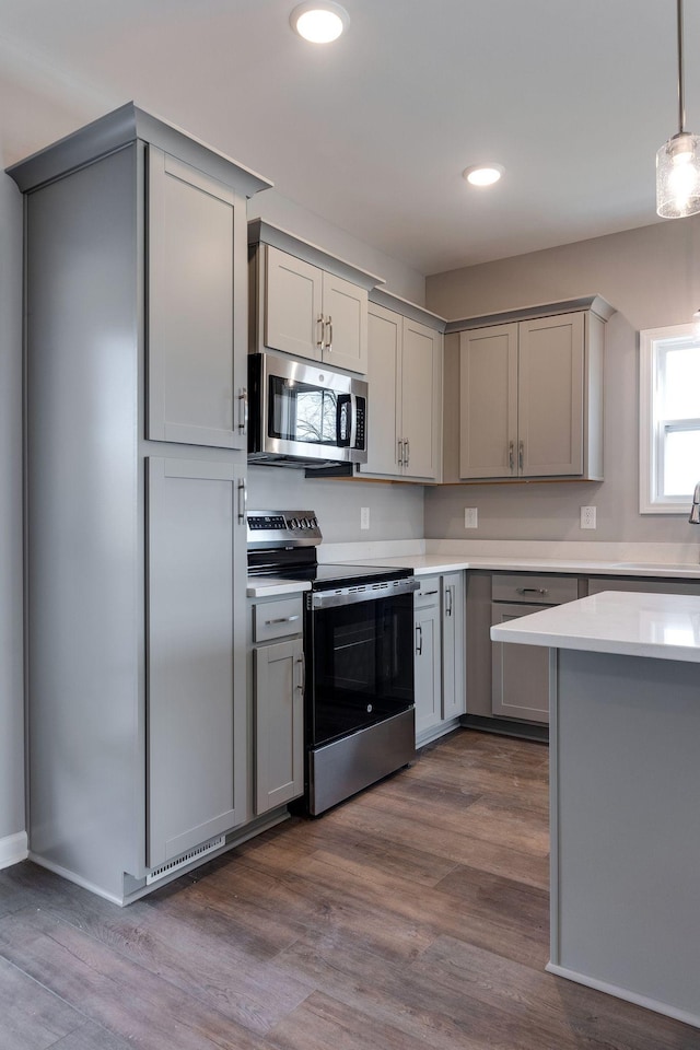 kitchen with dark wood-type flooring, hanging light fixtures, gray cabinets, and stainless steel appliances