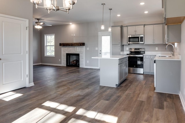 kitchen featuring a center island, stainless steel appliances, sink, hanging light fixtures, and gray cabinetry