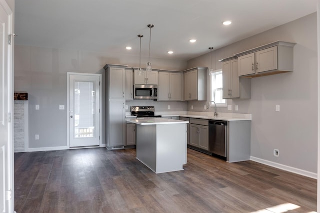 kitchen featuring gray cabinets, appliances with stainless steel finishes, hanging light fixtures, a kitchen island, and sink