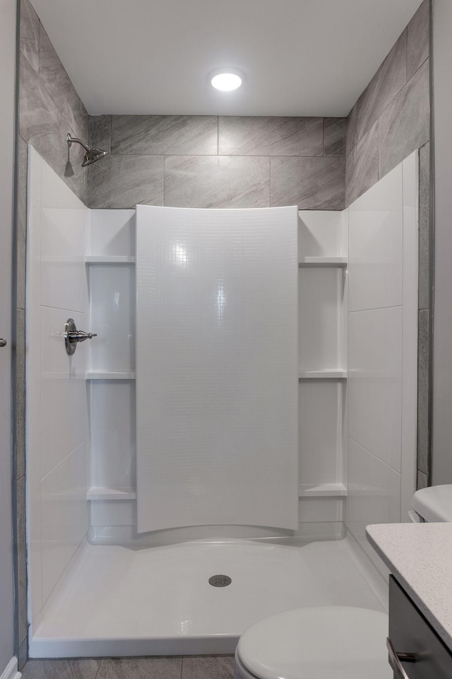 bathroom featuring toilet, a shower, and vanity