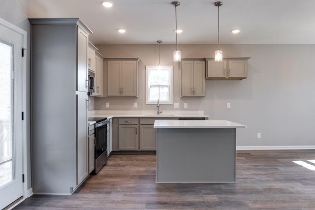 kitchen with appliances with stainless steel finishes, dark hardwood / wood-style flooring, sink, hanging light fixtures, and gray cabinetry