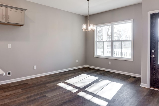 unfurnished dining area featuring dark wood-type flooring and a notable chandelier