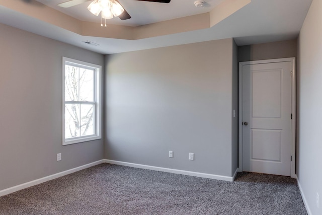 carpeted empty room featuring ceiling fan and a tray ceiling