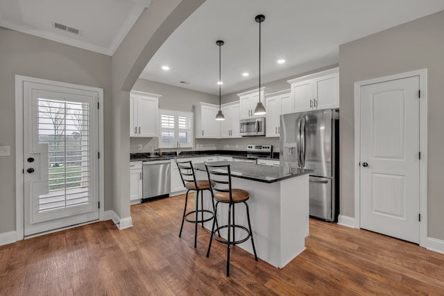 kitchen featuring white cabinetry, appliances with stainless steel finishes, wood-type flooring, and a center island