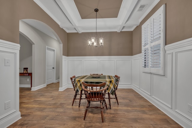 dining space featuring dark hardwood / wood-style flooring, an inviting chandelier, coffered ceiling, crown molding, and beam ceiling