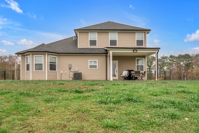 rear view of property with central AC unit and a yard