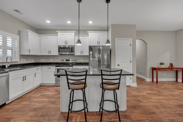 kitchen featuring white cabinets, sink, a kitchen island, pendant lighting, and appliances with stainless steel finishes