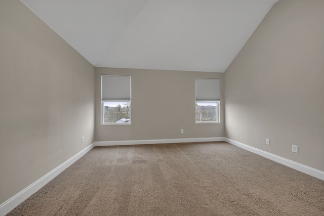 carpeted spare room with vaulted ceiling