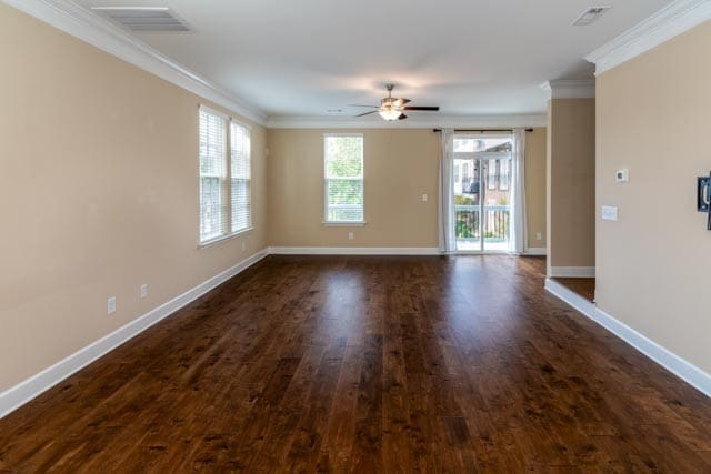 spare room with dark wood-type flooring, ceiling fan, and ornamental molding