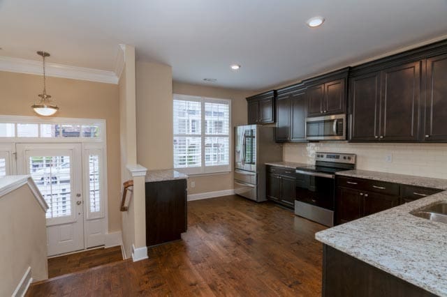 kitchen featuring light stone counters, ornamental molding, stainless steel appliances, dark hardwood / wood-style floors, and pendant lighting