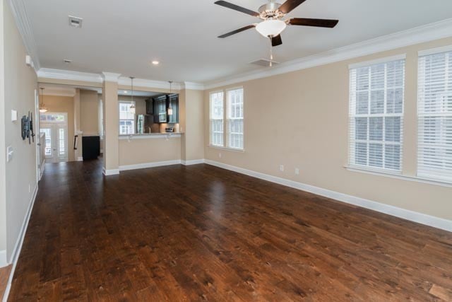 unfurnished living room with dark hardwood / wood-style floors, plenty of natural light, and crown molding