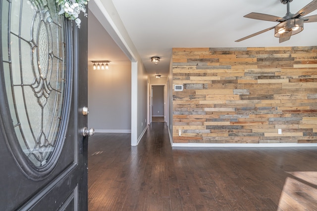 foyer entrance featuring dark hardwood / wood-style flooring, ceiling fan, and wood walls