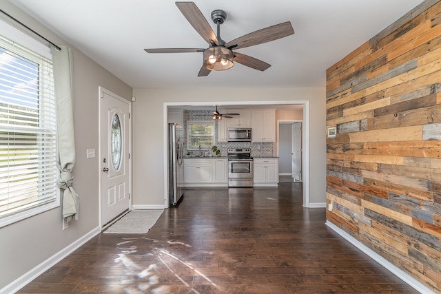 foyer featuring ceiling fan, wood walls, and dark wood-type flooring