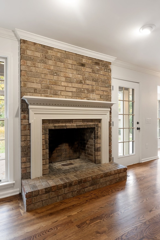 room details featuring wood-type flooring, crown molding, and a brick fireplace