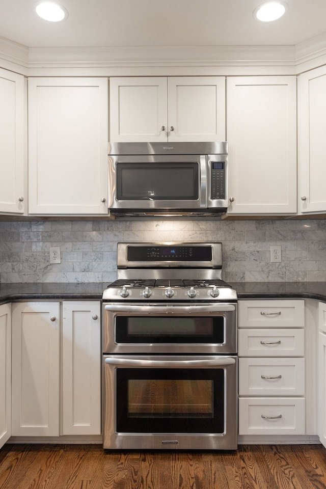 kitchen with white cabinets, dark wood-type flooring, and appliances with stainless steel finishes