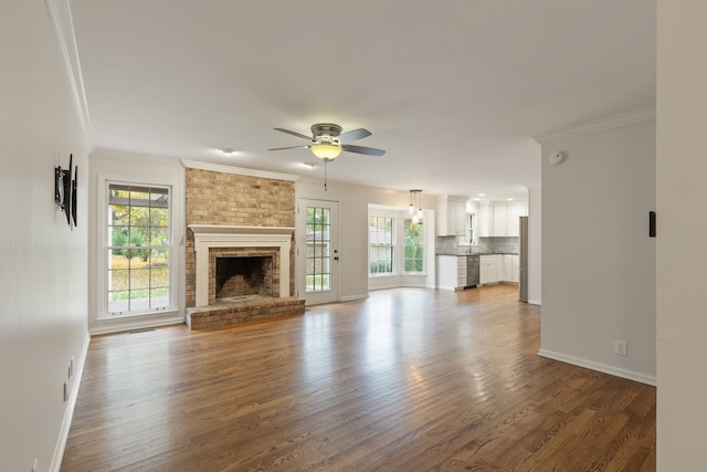 unfurnished living room featuring a brick fireplace, hardwood / wood-style flooring, ceiling fan, and ornamental molding