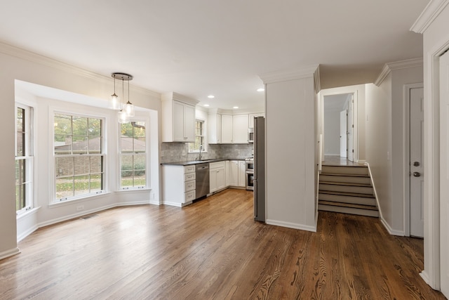 kitchen featuring stainless steel appliances, white cabinetry, sink, hanging light fixtures, and dark hardwood / wood-style flooring