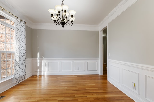 unfurnished dining area with light hardwood / wood-style floors, a notable chandelier, and crown molding