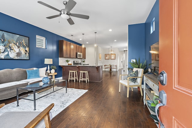 living room featuring ceiling fan and dark hardwood / wood-style floors