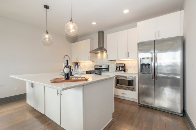 kitchen with a center island with sink, stainless steel appliances, white cabinets, dark wood-type flooring, and wall chimney exhaust hood