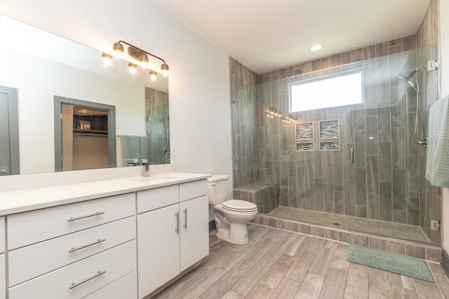 bathroom with hardwood / wood-style floors, vanity, toilet, and a shower with door