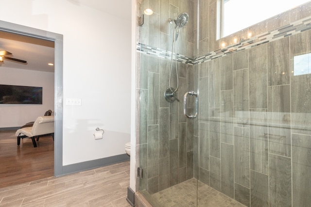 bathroom featuring toilet, an enclosed shower, wood-type flooring, and ceiling fan