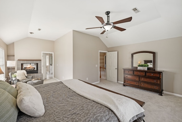 bedroom with ceiling fan, light carpet, a tile fireplace, and vaulted ceiling