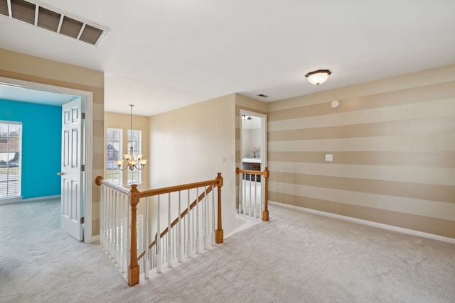 corridor featuring light carpet and a chandelier