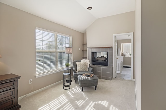 sitting room with a tile fireplace, light colored carpet, and lofted ceiling