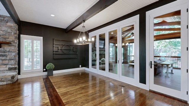 unfurnished dining area with beam ceiling, an inviting chandelier, and dark hardwood / wood-style flooring