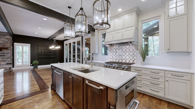 kitchen with sink, a kitchen island with sink, beamed ceiling, dark hardwood / wood-style floors, and white cabinetry