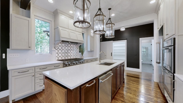 kitchen with a center island with sink, sink, dark hardwood / wood-style floors, decorative light fixtures, and white cabinets