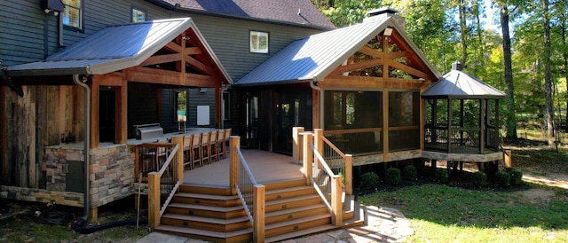 rear view of house with a wooden deck and a sunroom