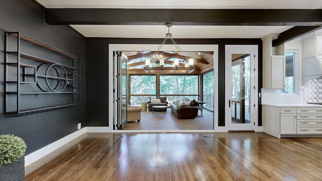 unfurnished dining area with dark hardwood / wood-style floors, an inviting chandelier, and vaulted ceiling with beams