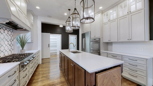 kitchen featuring stainless steel appliances, a center island with sink, sink, white cabinetry, and hardwood / wood-style floors