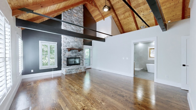 unfurnished living room with beam ceiling, high vaulted ceiling, wood-type flooring, a stone fireplace, and wood ceiling