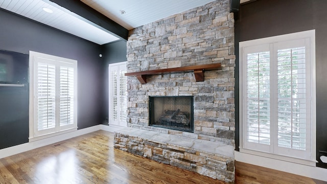 unfurnished living room featuring a fireplace, beamed ceiling, hardwood / wood-style flooring, and wooden ceiling