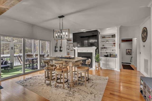 dining area with light hardwood / wood-style flooring, a chandelier, and crown molding