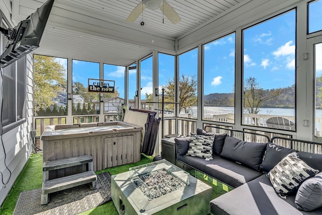 sunroom / solarium with a wealth of natural light, a hot tub, a water view, and ceiling fan