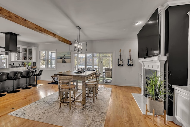 dining area with plenty of natural light, a notable chandelier, light hardwood / wood-style floors, and beam ceiling