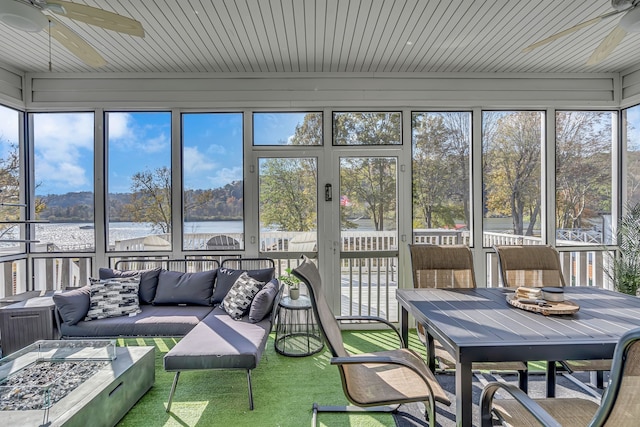 sunroom featuring wooden ceiling, ceiling fan, plenty of natural light, and a water view