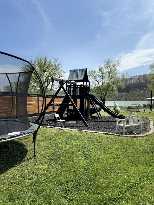 view of play area with a water view, a lawn, and a trampoline