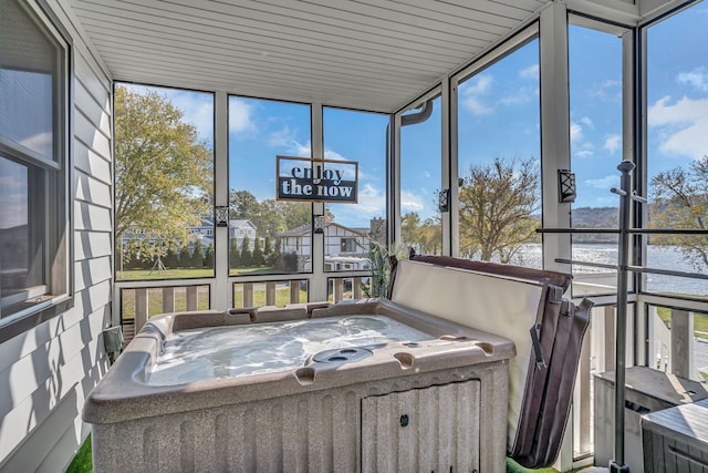 sunroom / solarium featuring a hot tub, a water view, and plenty of natural light