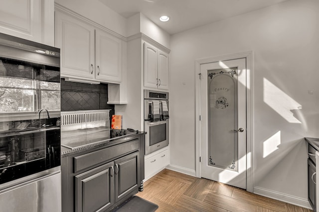 kitchen featuring white cabinets, stainless steel double oven, black stovetop, and tasteful backsplash