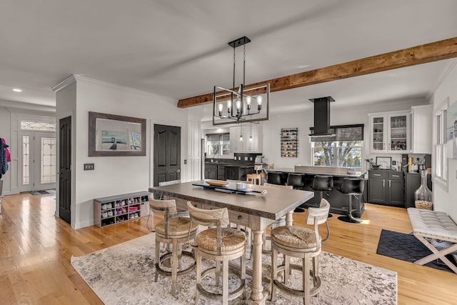 dining space featuring beam ceiling, a chandelier, light hardwood / wood-style floors, and crown molding