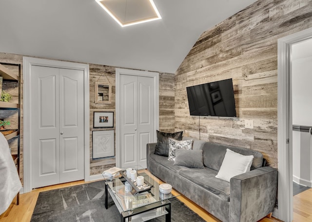 living room featuring wooden walls, lofted ceiling, and hardwood / wood-style floors