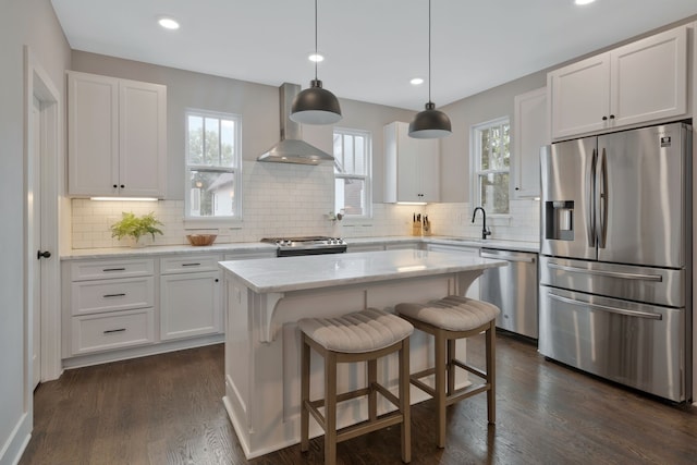 kitchen with white cabinetry, stainless steel appliances, decorative light fixtures, and a center island